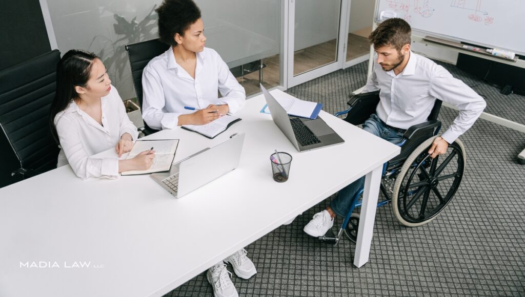 Disable man in a wheelchair collaborating with coworkers in an office
