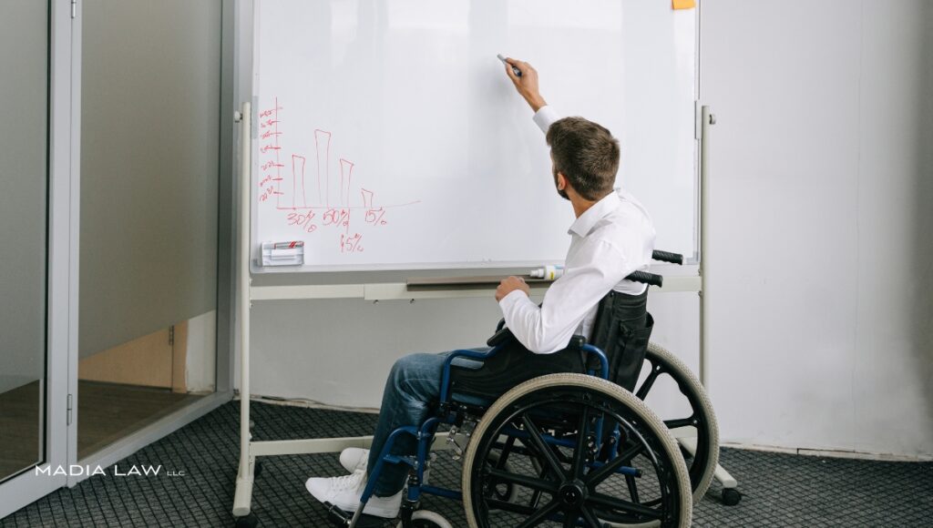 An employee with a physical disability presenting data at a whiteboard